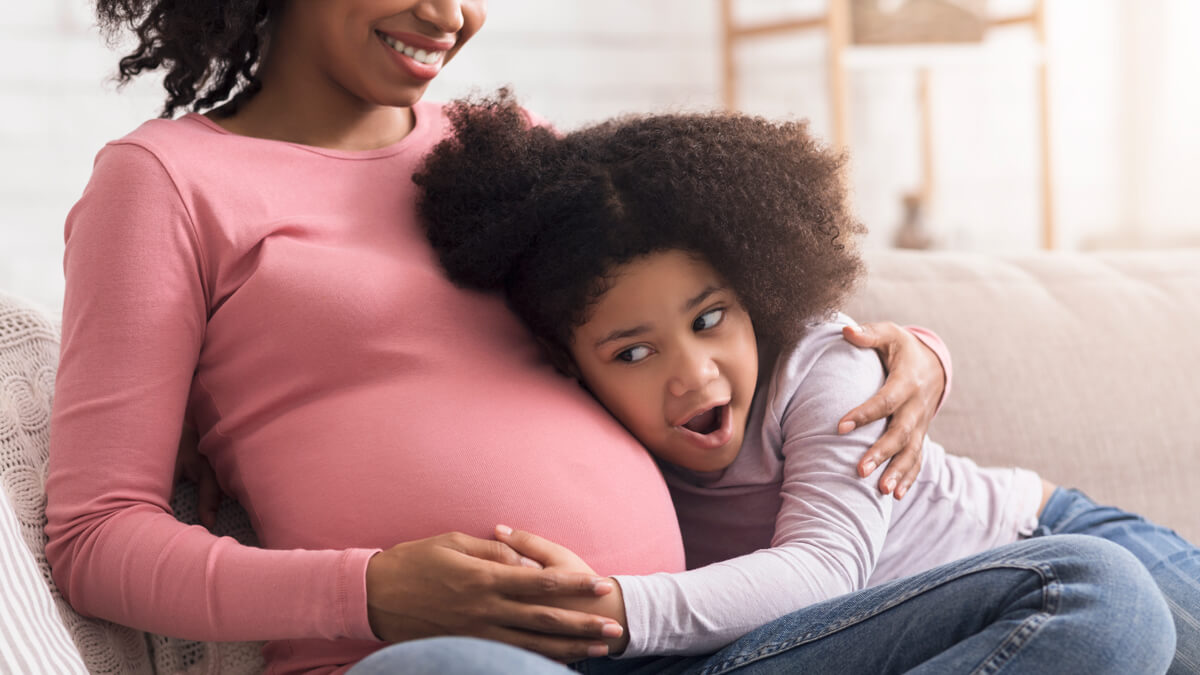 Girl listening to her mom's pregnant belly
