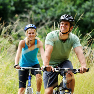 Man and woman riding bikes in a field.