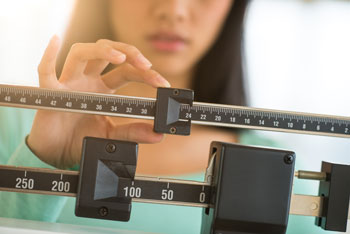 woman checking her weight on a scale