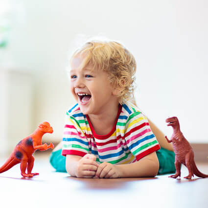 smiling kid playing with dinosaur toys