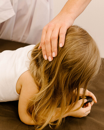 Chiropractor gently working with a young girl during a pediatric visit