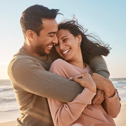 man and woman hugging on beach during sunset