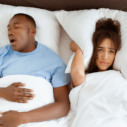 man snoring while wife is awake in bed