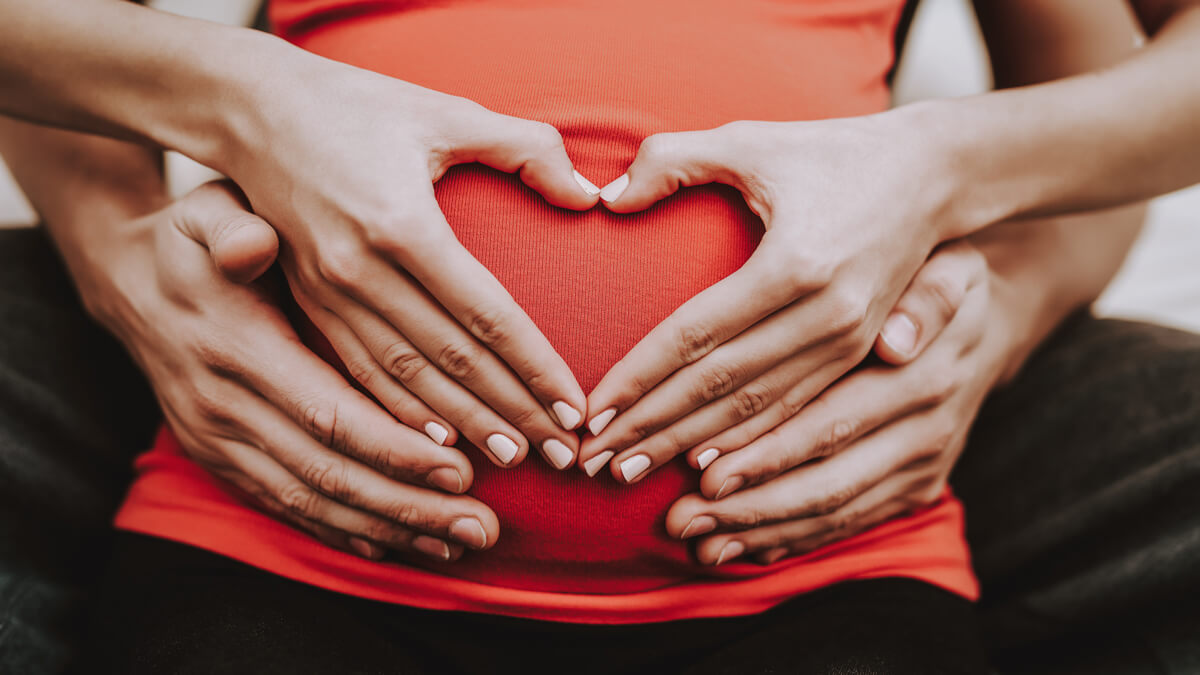 couple makes heart on pregnant belly 