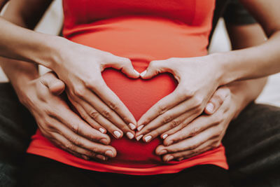 couple makes heart on pregnant belly