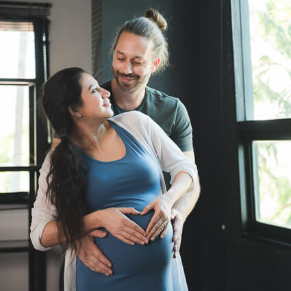 pregnant woman being hugged from behind by her partner