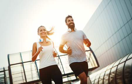 Two smiling athletes running outdoors