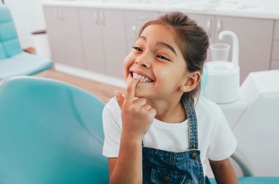 little girl smiling showing her teeth to the dentist