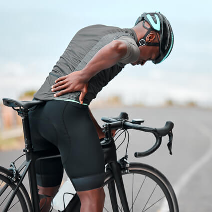 Cyclist stopped on road holding back in pain