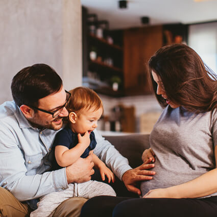 dad and toddler boy touching moms pregnant stomach