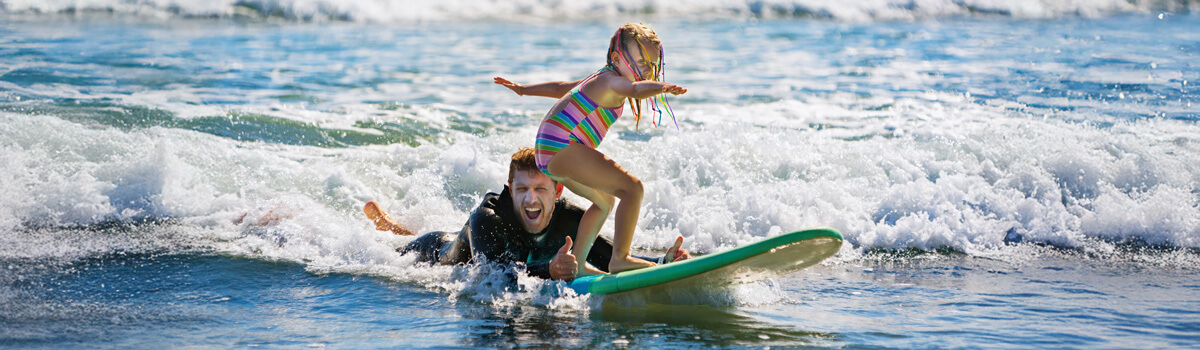 dad teaching daughter to surf