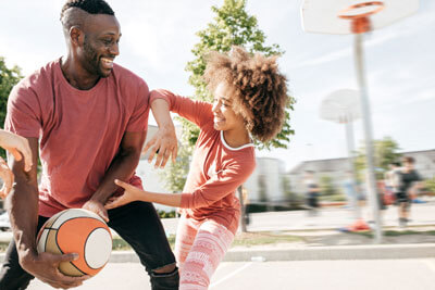 Dad and daughter playing basketball