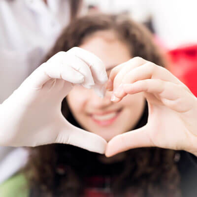 Dentist and patient forming a heart shape with their hands