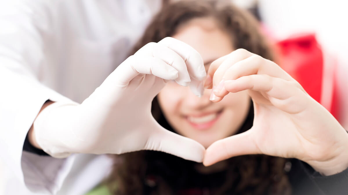 Woman making heart with hands by teeth