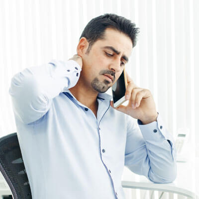 man on phone holding neck in pain