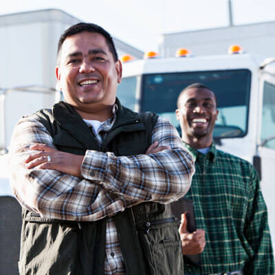 two smiling drivers standing near their trucks
