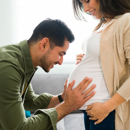 Father cradling pregnant wife's tummy