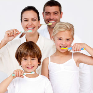 Family of four brushing teeth