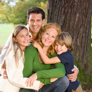 Family hugging by a tree