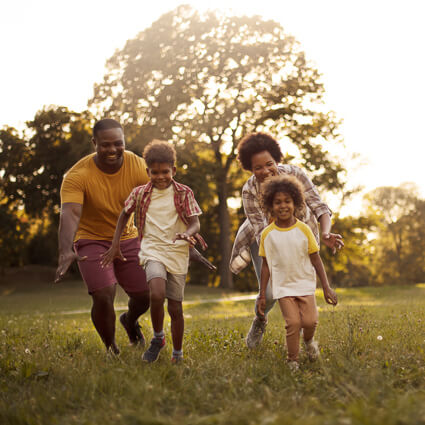 mom, dad, and 2 kids playing outdoors