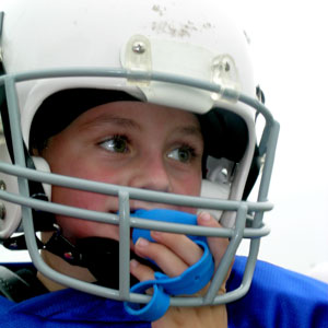 Child with mouthguard and football helmet