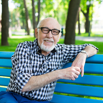 Elderly man sitting outdoors on bright, blue bench