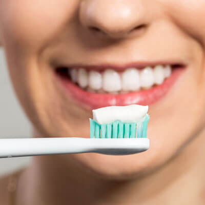 closeup of womans mouth holding toothbrush with toothpaste