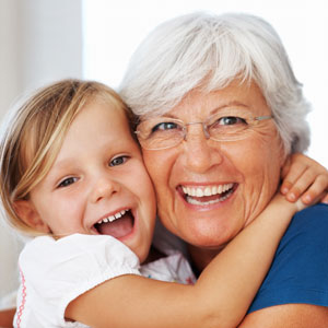Older gray haired woman hugging little girl