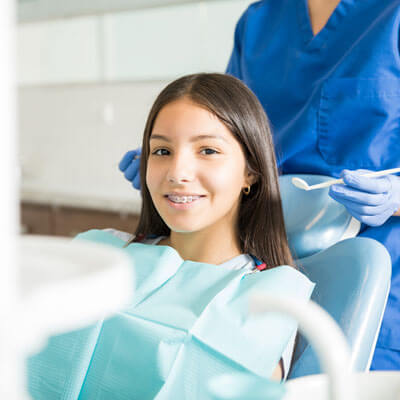 girl with braces sitting in a dentist's chair