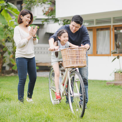 mom & dad teaching kid to ride a bike
