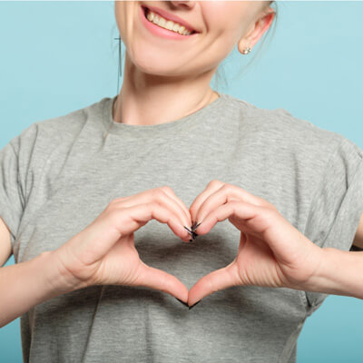 woman making heart with hands wearing grey shirt