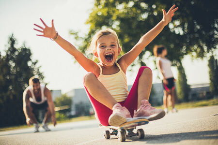 little girl sitting on skateboard smiling