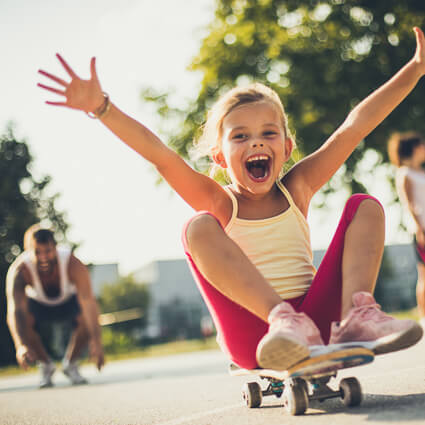 smiling kid sitting on a skateboard