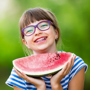 young girl with orthodontics holding watermelon