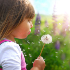 girl blowing a flower