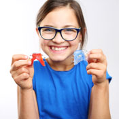 Young girl with glasses holding dental retainer