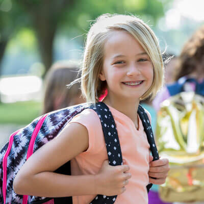 girl with backpak at school with braces