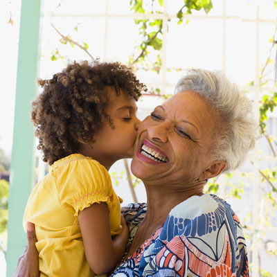 Little girl kissing elderly woman with white hair