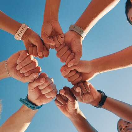 group of people putting fists into a circle