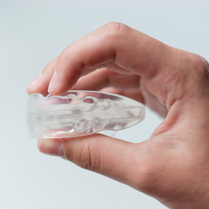 person holding a clear mouthguard