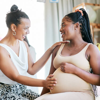 woman touching a pregnant friend's stomach