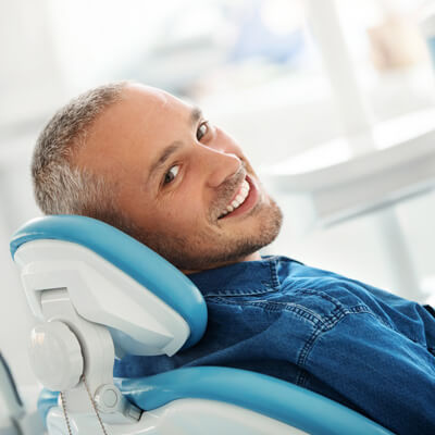 Man sitting in dental chair and smiling at the camera