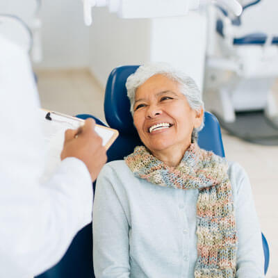 Happy, smiling older woman with gray hair talking to dentist