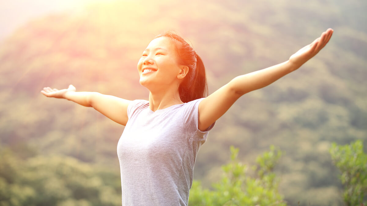 Happy woman with arms out in mountains