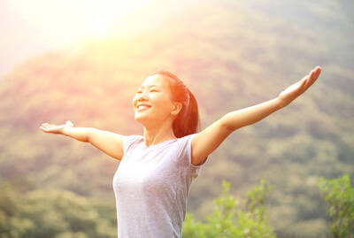 woman smiling with arms out standing on mountain