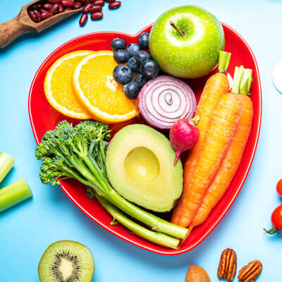 A heart-shaped plate with healthy fruits and vegetables on it.
