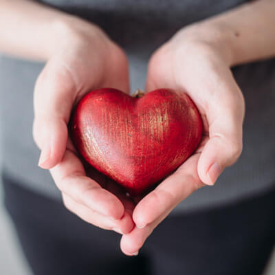 Woman holding a wooden carving of a heart in her hands