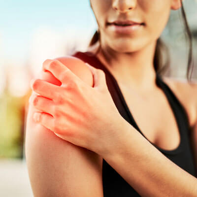 A woman grabbing her shoulder in pain.