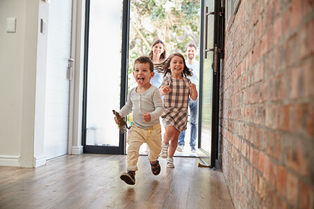 Smiling family of four entering a house
