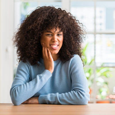 lady at table holding jaw